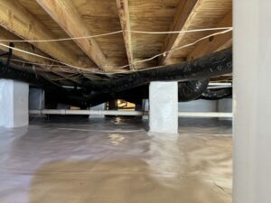 A clean crawl space with plastic sheeting on the floor, exposed wooden beams above, and HVAC ducts running across the space.