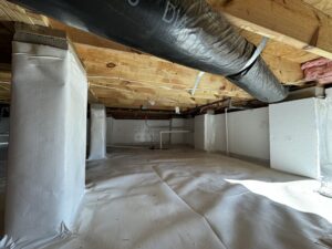 A clean, dry crawl space with insulated walls and a plastic vapor barrier on the floor. Ductwork and wooden beams are visible above.