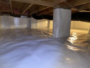 Crawl space with white vapor barrier lining, exposed wooden beams above, and insulated ductwork running across.