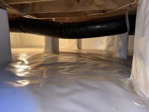 A crawl space with sealed floors and walls, featuring wrapped support columns and an insulated duct.